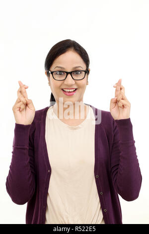 Jeune femme heureuse crossing fingers against white Banque D'Images