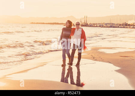 Portrait of happy mother and daughter holding hands de passer du temps ensemble à rire et marcher sur la plage au coucher du soleil la lumière dans une famille heureuse Banque D'Images