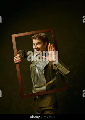 Chevalier médiéval sombre sur fond de studio. Portrait dans la clé de l'homme faible brutal en costume rétro tradishional de hidalgo espagnol. Les émotions humaines, la comparaison des époques et les expressions du visage concept Banque D'Images