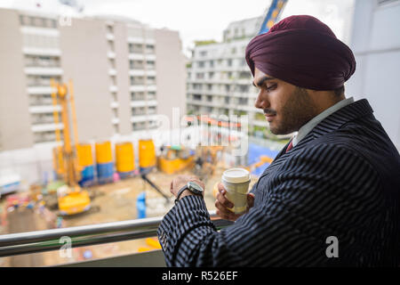 Indian businessman looking at construction site en développement avec des gratte-ciel Banque D'Images