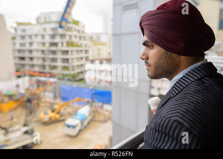 Indian businessman looking at construction site en développement avec des gratte-ciel Banque D'Images