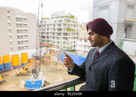 Indian businessman looking at construction site en développement avec des gratte-ciel Banque D'Images