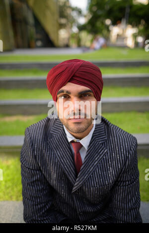 Homme d'affaires indien avec turban assis à l'extérieur en ville Banque D'Images