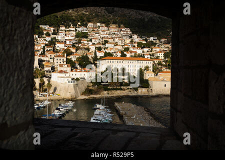 Port de Dubrovnik et maisons sur mountain vu à travers une fenêtre dans le mur de la forteresse, Croatie Banque D'Images