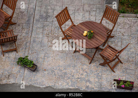 Vue de dessus d'un restaurant avec chaises en bois, orné de fruits, en face d'un hôtel Banque D'Images