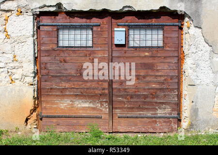 Portes de garage fait de petits panneaux en bois avec une couleur brune pâle et deux petites fenêtres protégées par des barres de métal à côté de boîte aux lettres Banque D'Images