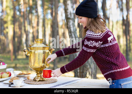 Jeune femme portant jersey avec hat verser un peu d'aide de thé théière samovar russe vintage Banque D'Images