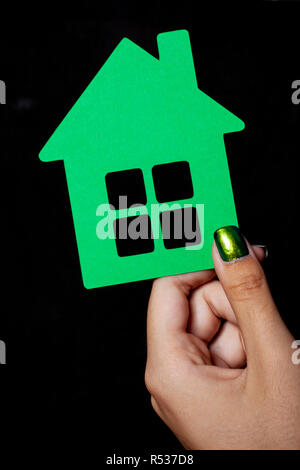 Hand holding a little green paper house - Fond noir Banque D'Images