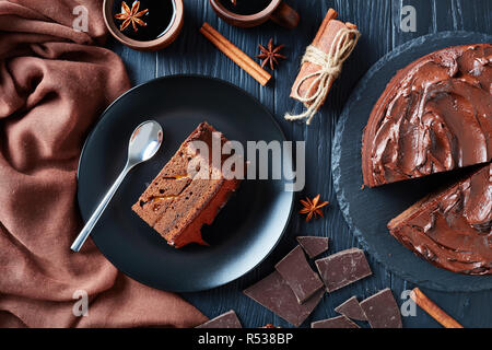 Portion de gâteau au chocolat avec de la confiture d'abricot garnie de remplissage ganache chocolat servi sur une plaque noire avec du vin dans des tasses d'argile sur une rustique bla Banque D'Images
