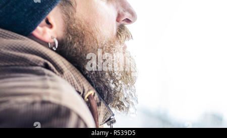 Barbe couverte de glaçons et gouttelettes congelées. Portrait d'hiver jeune homme de profil. Banque D'Images