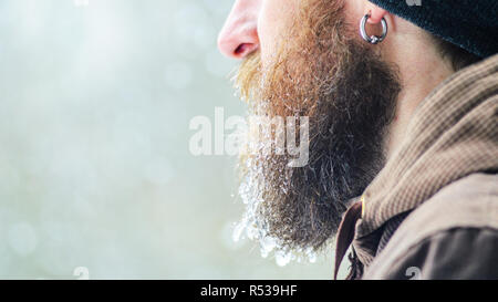 Barbe couverte de glaçons et gouttelettes congelées. Portrait d'hiver jeune homme de profil. Banque D'Images