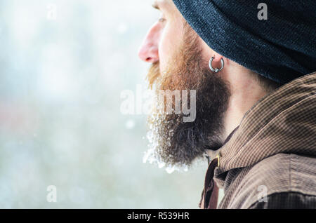 Barbe couverte de glaçons et gouttelettes congelées. Portrait d'hiver jeune homme de profil. Banque D'Images