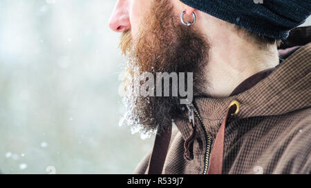 Barbe couverte de glaçons et gouttelettes congelées. Portrait d'hiver jeune homme de profil. Banque D'Images