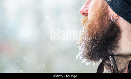 Barbe couverte de glaçons et gouttelettes congelées. Portrait d'hiver jeune homme de profil. Banque D'Images