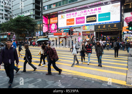 Personnes marchant sur Nathan Road avec Chungking Mansions entrée dans l'arrière-plan, un célèbre bâtiment complexe avec les hôtels et les boutiques, Hong Kong Banque D'Images