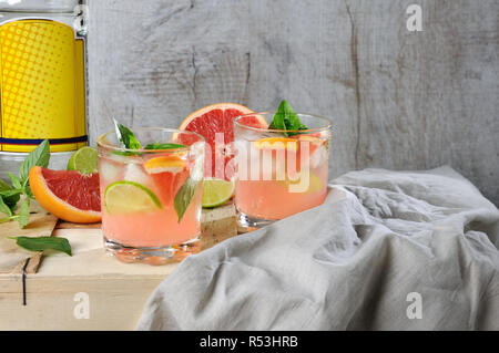 Cocktail de London Dry Gin jus pressé avec du pamplemousse rouge et les feuilles de basilic citron, de délicates tranches de lime et de cubes de glace réfrigéré. Banque D'Images