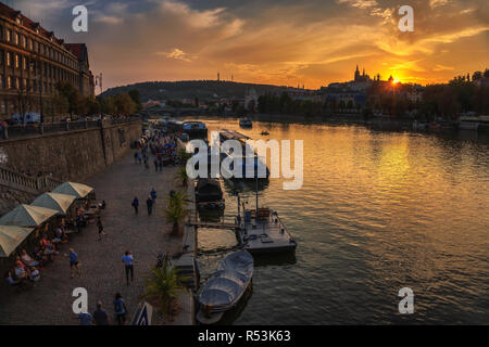 Les gens marchent le long de la rivière Vltava à Prague au coucher du soleil Banque D'Images