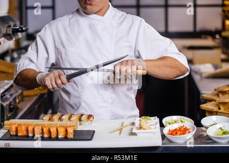 Chef chinois posant avec des couteaux Banque D'Images