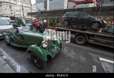 Bonhams, New Bond Street, London, UK. 29 novembre 2018. Jaguar historique les voitures de course arrivent à Bonhams au centre de Londres à côté d'autres voitures de course haute performance et voitures de route exceptionnelle. Faits saillants comprennent une Classe Le Mans Jaguar XJ-winning220C conduit par David Coulthard (£800 000), 2,200,000-2,Lister Jaguar dite nodulaire (£2,200,000-2,800 000). De droit : 1937 Lagonda LG45 Rapide Tourer est déchargé à New Bond Street, estimation £750,000-850,000, l'un des 25 construits. Une voiture en stationnement illégal sur New Bond Street est supprimé. Credit : Malcolm Park/Alamy Live News. Banque D'Images