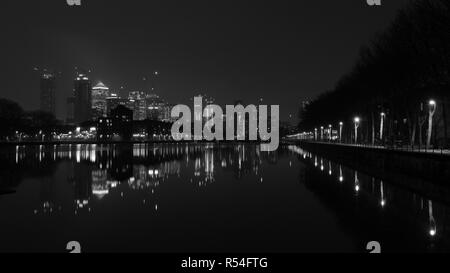 Nuit au Groenland Dock area à Londres. Ciel propre et claire réflexions sur l'eau et des lumières sur le chemin près du dock. Canary Wharf sur arrière-plan. Banque D'Images