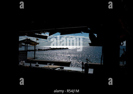 Voir encadré d'une baie de la mer Noire, près de la ville de Balchik, Bulgarie par l'ouverture d'une promenade sur la plage. Silhouettes des objets, par. Banque D'Images