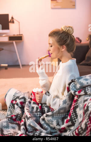 Femme en blanc holding christmas gingerbread cookie et tasse de chocolat chaud Banque D'Images