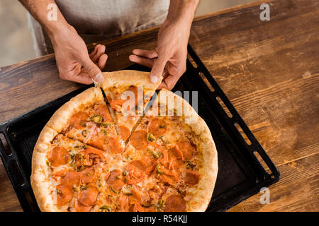 Cropped shot of man holding pizza slice sur la plaque de cuisson Banque D'Images