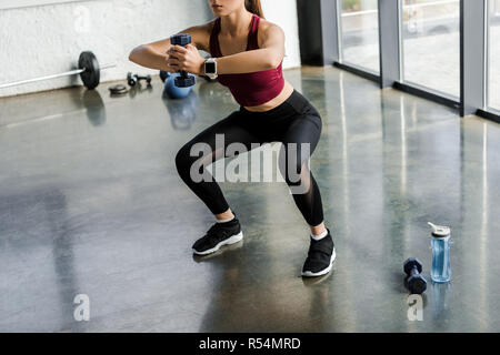 Portrait de la sportive sportive faisant de l'exercice de squat avec haltère au centre de remise en forme Banque D'Images