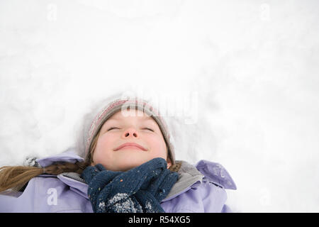 Girl lying on snow Banque D'Images