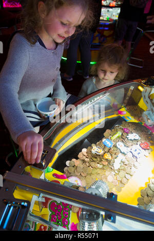 Jeune fille âgée de 6 ans / 6 ans jouant sur un coin pusher traditionnels populaires / pièces poussant en jeu pier arcade fun house. UK. (98). Banque D'Images