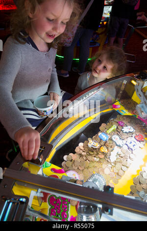 Jeune fille âgée de 6 ans / 6 ans jouant sur un coin pusher traditionnels populaires / pièces poussant en jeu pier arcade fun house. UK. (98). Banque D'Images