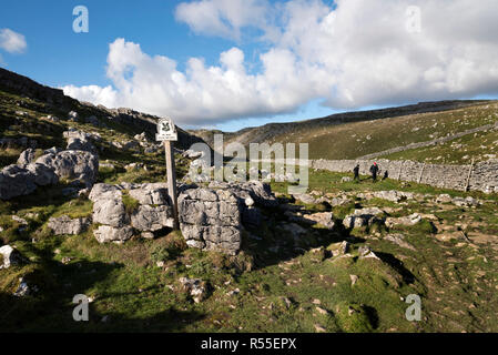 Les marcheurs dans la vallée au-dessus de roches calcaires Malham Cove, dans le Yorkshire Dales National Park, Royaume-Uni. Banque D'Images