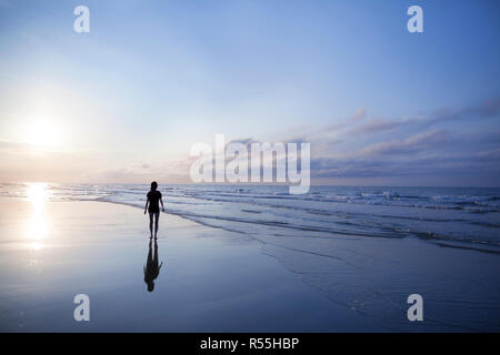 Femme marche sur la plage au lever du soleil Banque D'Images