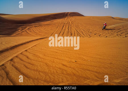 Racer sur la moto dans le désert de dunes de sable de Dubaï. Banque D'Images