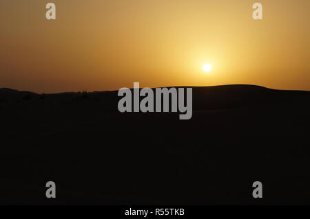Coucher du soleil dans le désert de dunes de sable de Dubaï. Banque D'Images