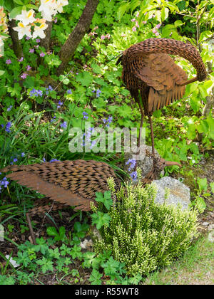 Sculptures de fer rouillé deux grues dans un printemps jardin Devon Banque D'Images