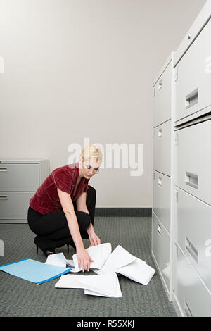 Woman picking up papier a chuté Banque D'Images