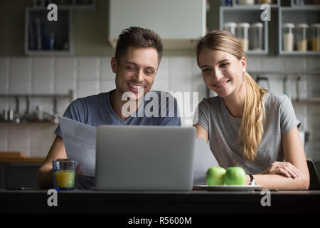 Happy young couple smiling and looking at laptop écran Banque D'Images