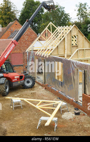 Buckingham, Royaume-Uni - Octobre 13, 2016. La machinerie lourde est utilisée pour ajouter les fermes de toit d'une maison à ossature bois extension dans le Buckinghamshire, Royaume-Uni Banque D'Images