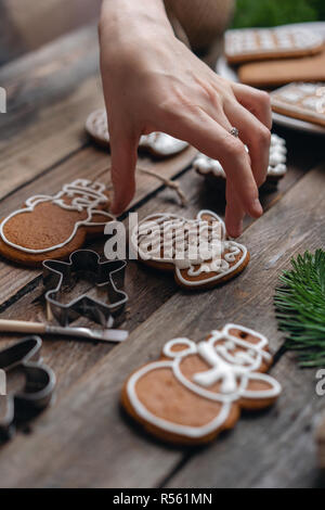 Les cookies dans la forme de moufles. Une jeune fille décore ginger cookies hiver matin de Noël. Femme attire cerise sur le miel d'épices . Table marron en bois. copier l'espace. Banque D'Images