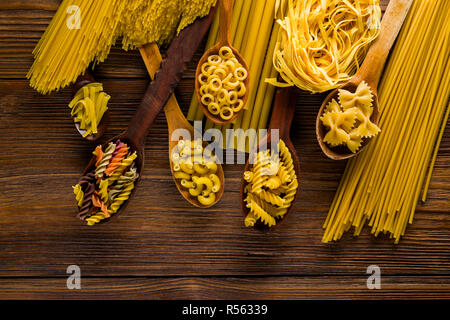 Une variété de pâtes crues et les spaghettis sur des cuillères en bois Banque D'Images