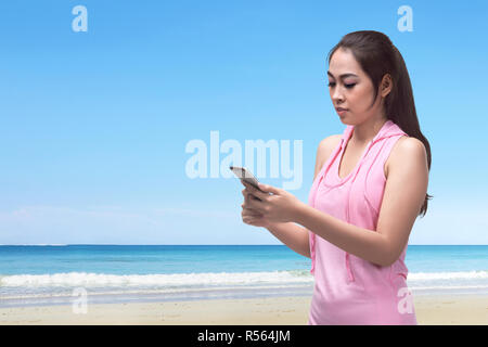 Belle asiatique femme marche tout en utilisant son téléphone Banque D'Images