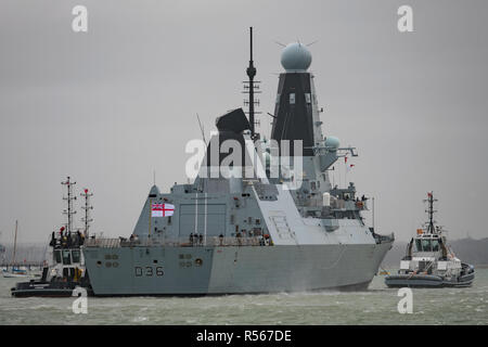 Le navire de guerre de la Marine royale britannique, le HMS Defender (Type 45 destroyer) d'être aidé par des remorqueurs dans le port de Portsmouth, Royaume-Uni le 29 novembre 2018. Banque D'Images