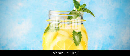 Cocktail pot de limonade et de feuilles de menthe sur fond bleu table en bois de l'eau naturelle de citron fait maison avec un verre de soda et de tranches de fruits st potable Banque D'Images