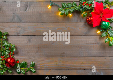 Houx de Noël avec des ornements, poinsettia, lumières et les baies sur un fond de bois Banque D'Images