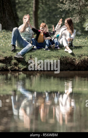 Les parents et les enfants donnant à chaque autre un cinq sur une promenade dans le parc Banque D'Images