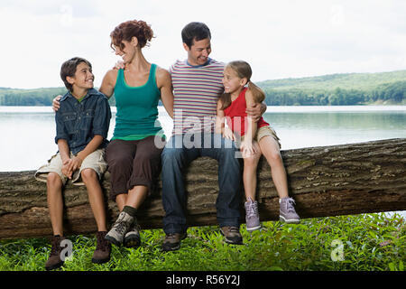 Family sitting on a log Banque D'Images