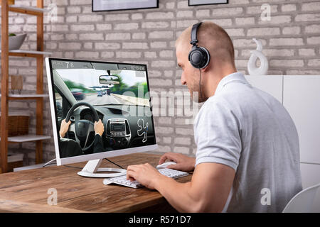 Jeune homme avec jeu de voiture Jeu de casque sur l'ordinateur plus de 24 Banque D'Images