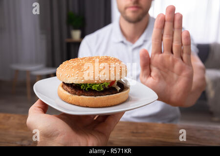 Close-up de la main d'un homme refusant Burger offert par personne Banque D'Images