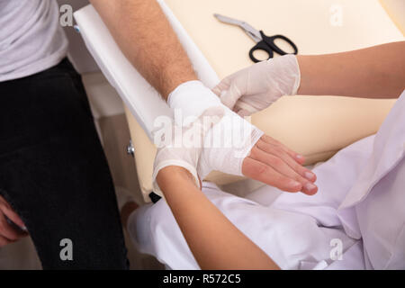 Close-up of Doctor Lier Bandage sur la main de l'homme blessé en clinique Banque D'Images